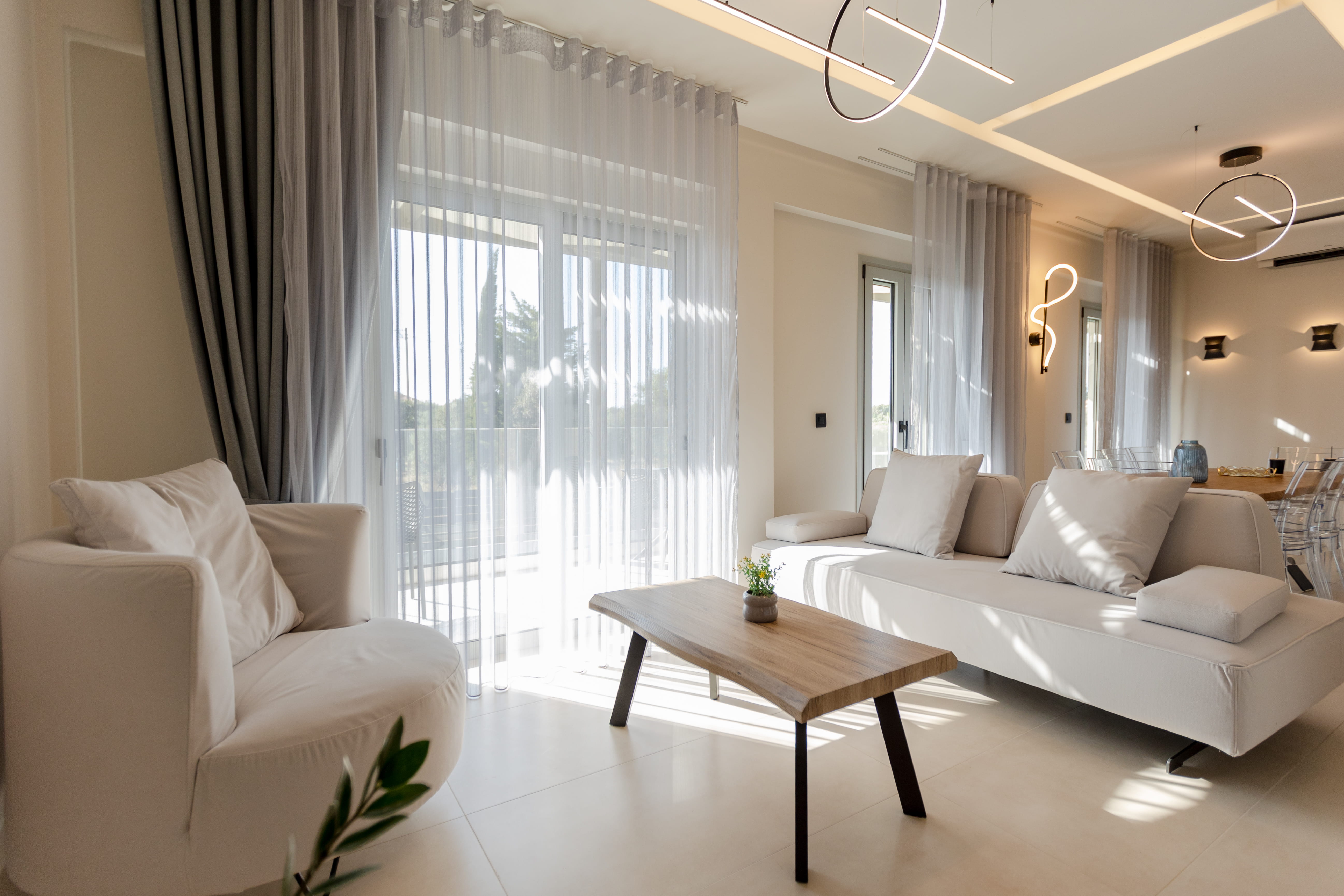 Bright open-plan living room interior at Infinity Lefkas villa with sheer curtains and designer lighting