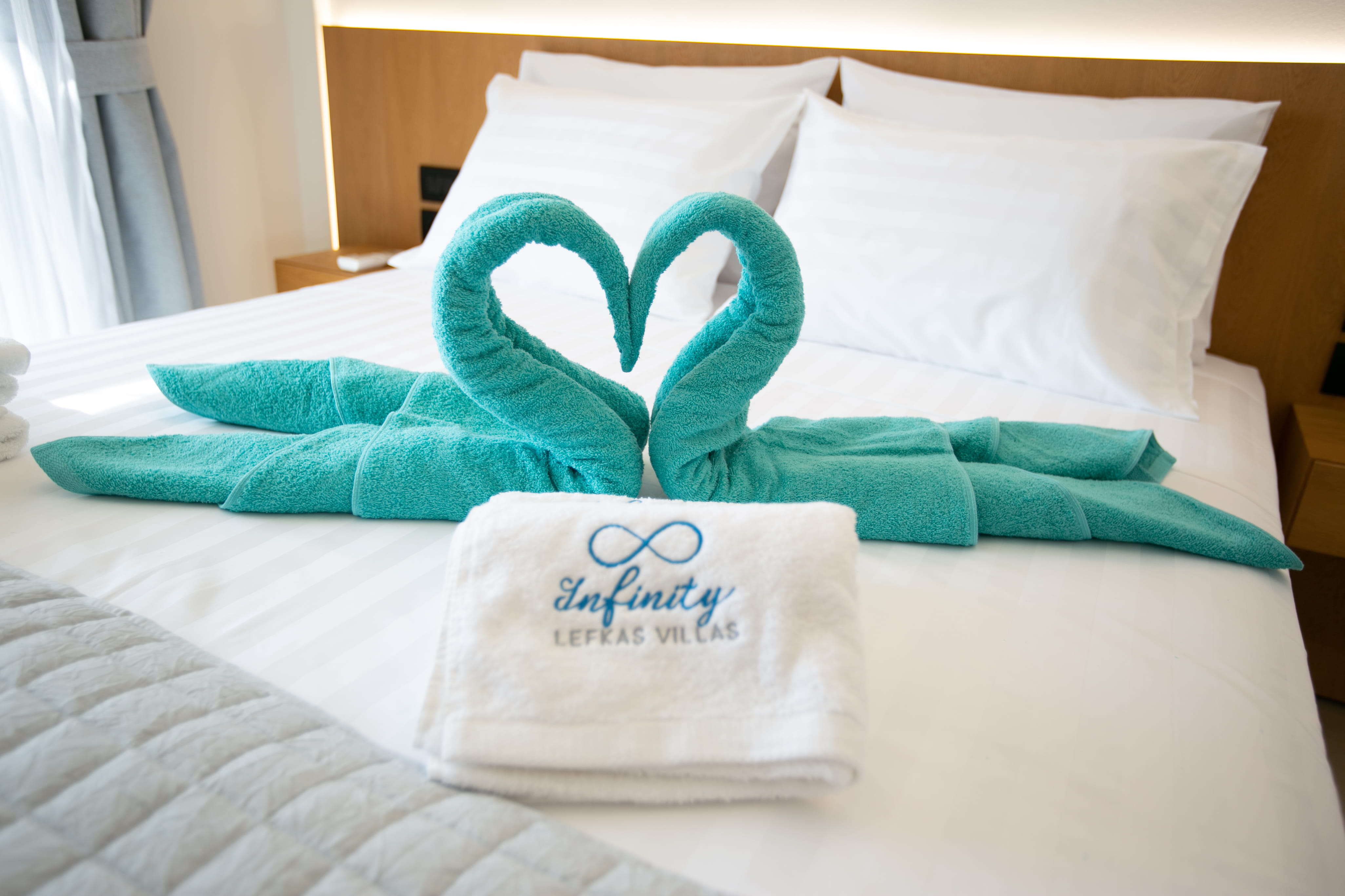 Infinity Lefkas branded towel welcome detail with swan arrangement on bed