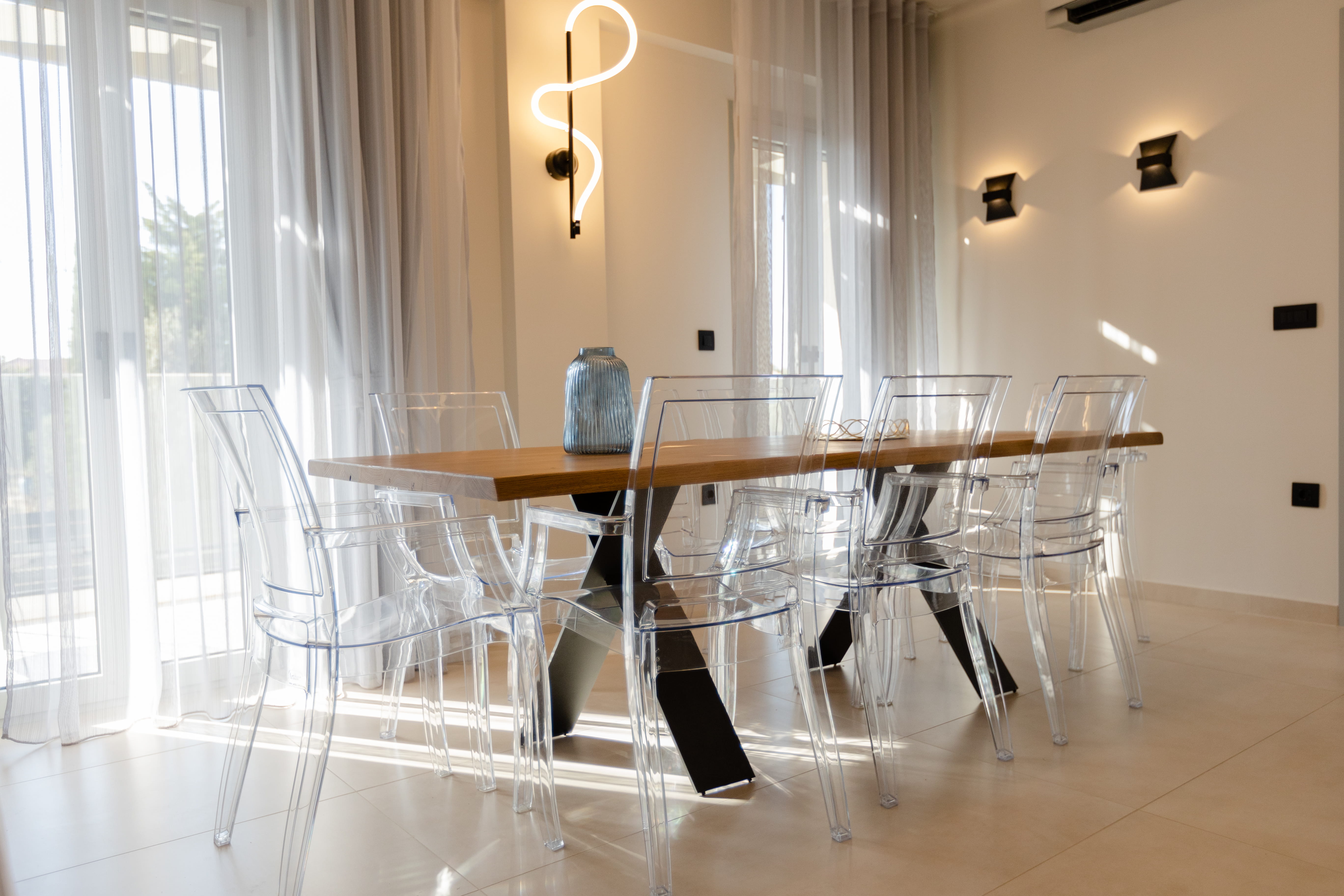 Elegant dining area with ghost chairs and wood table at Infinity Lefkas villa Lefkada Greece